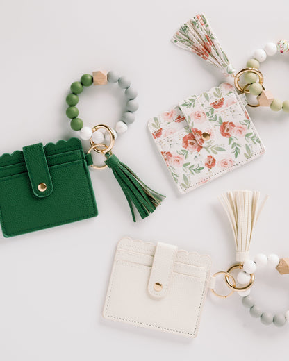 Green, floral, and white cardholders with tassels and bead keyrings on a white background.