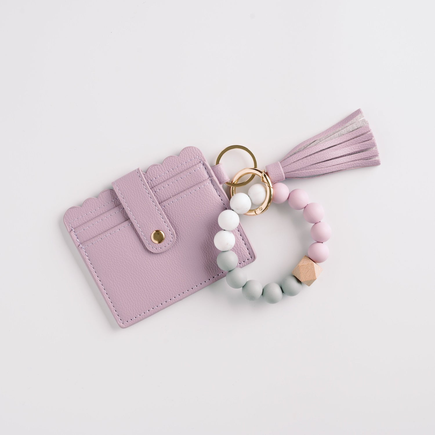 Lilac cardholder with scalloped edges, gold button, bead keychain in pastels, and a tassel.