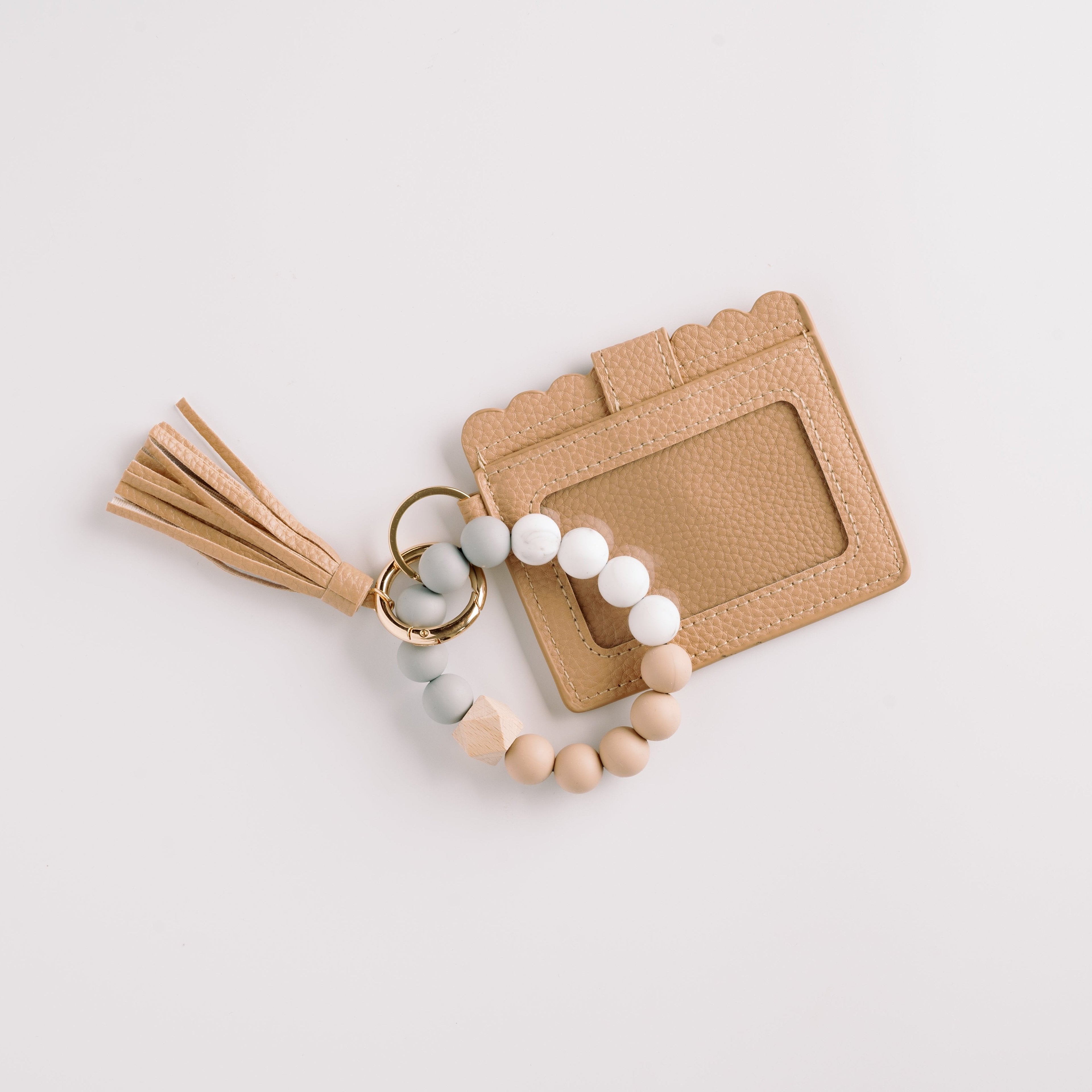 Beige cardholder with scalloped edges, beaded keychain in white, gray, and beige, and a tassel.