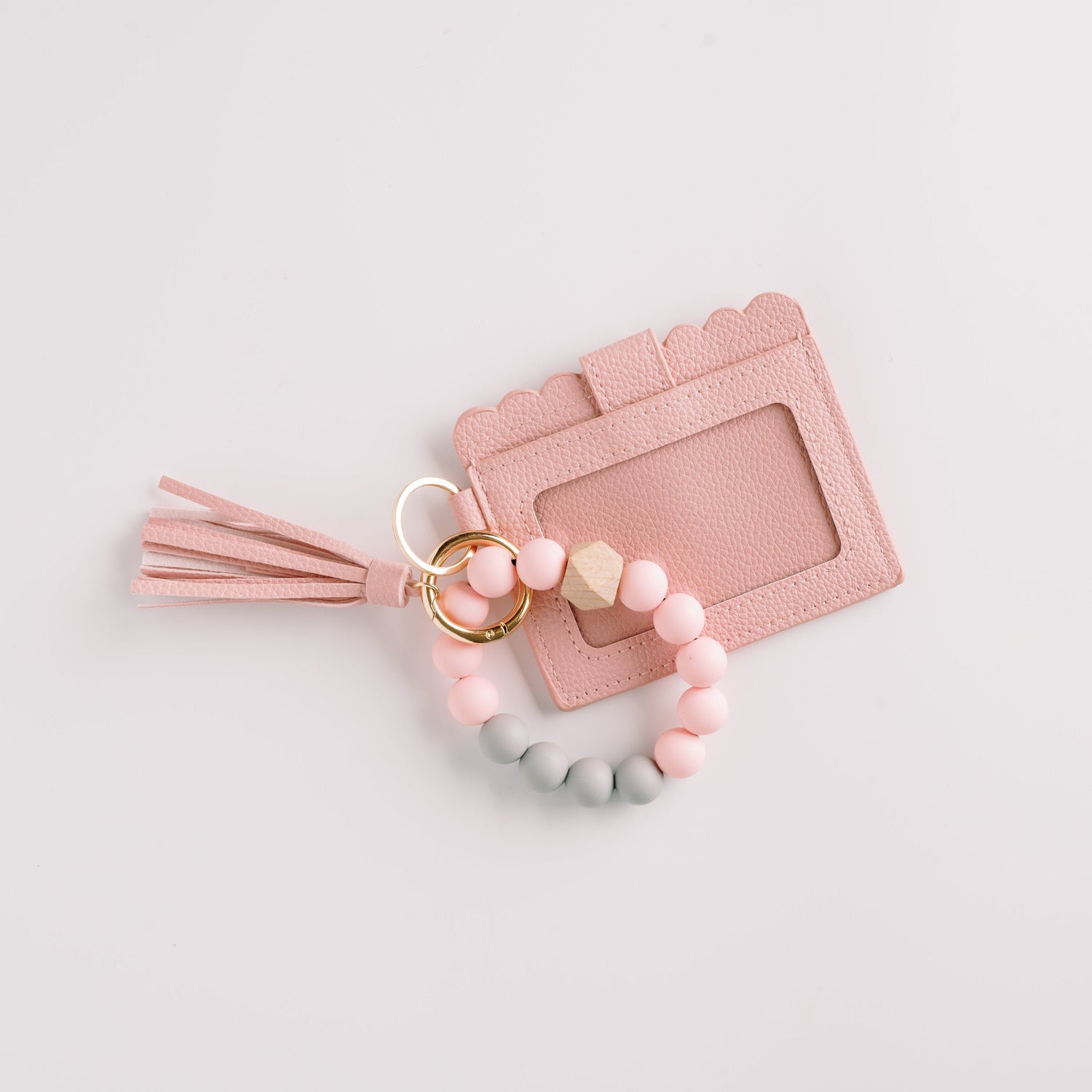 Pink cardholder with a tassel, linked to a keyring of pastel pink and gray beads on white.