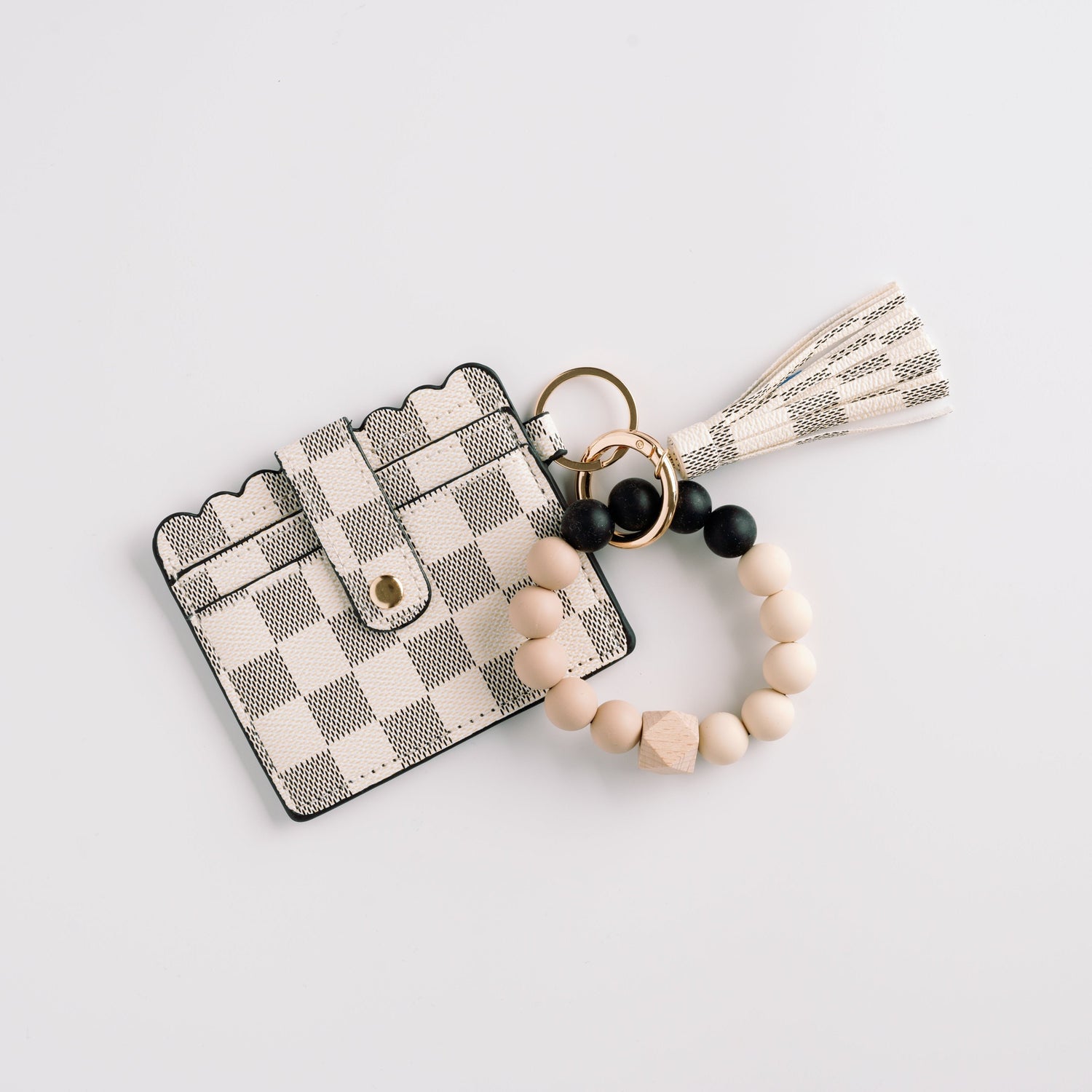 Checkered card holder with scalloped edge, attached beaded keychain, and tassel on white.