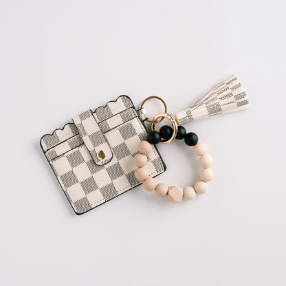 Checkered card holder with scalloped edge, attached beaded keychain, and tassel on white.
