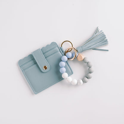 Light blue cardholder with a tassel and beaded keychain in pastel blue, white, and gray beads.