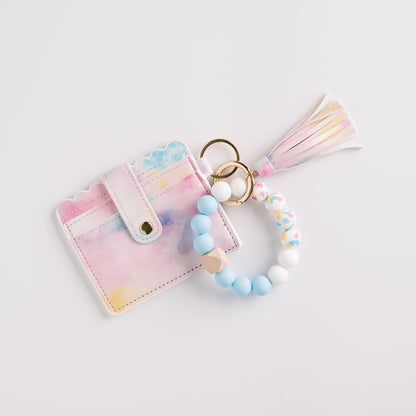 Pastel cardholder with scalloped edges, beaded keychain in blues and whites, and a tassel charm.