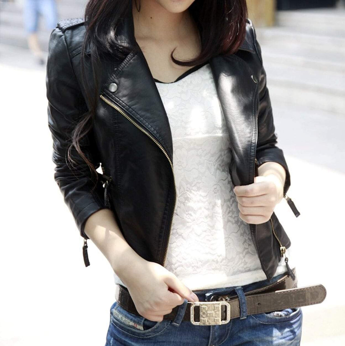 Person wearing a black leather jacket, white lace top, and blue jeans with a belt.