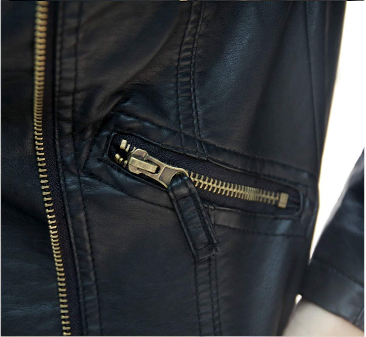 Close-up of a black leather jacket with a brass zipper and detailed stitching.