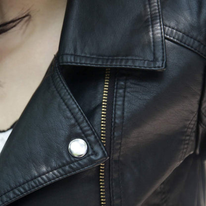 Close-up of black leather jacket with silver button and gold zipper detail.